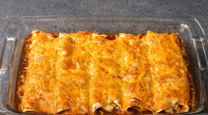 Creamy red chicken enchiladas baked with cheddar and mozzarella in a glass baking dish